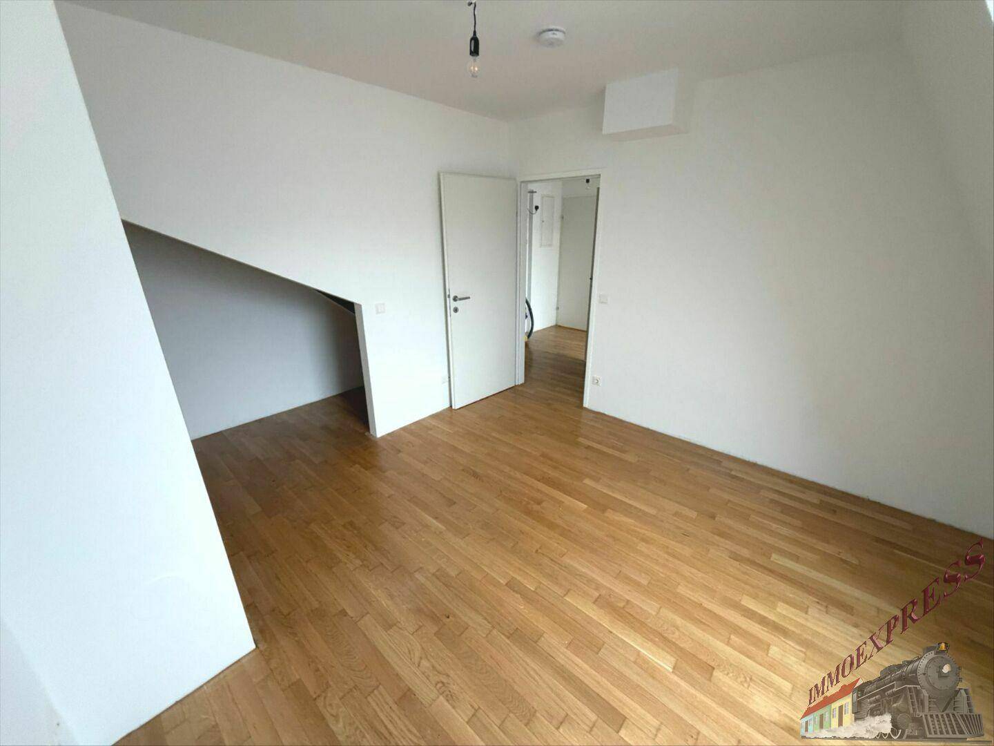 Geräumiges Schlafzimmer im Dachgeschoss mit Holzboden und Zugang zu einem weiteren Raum.