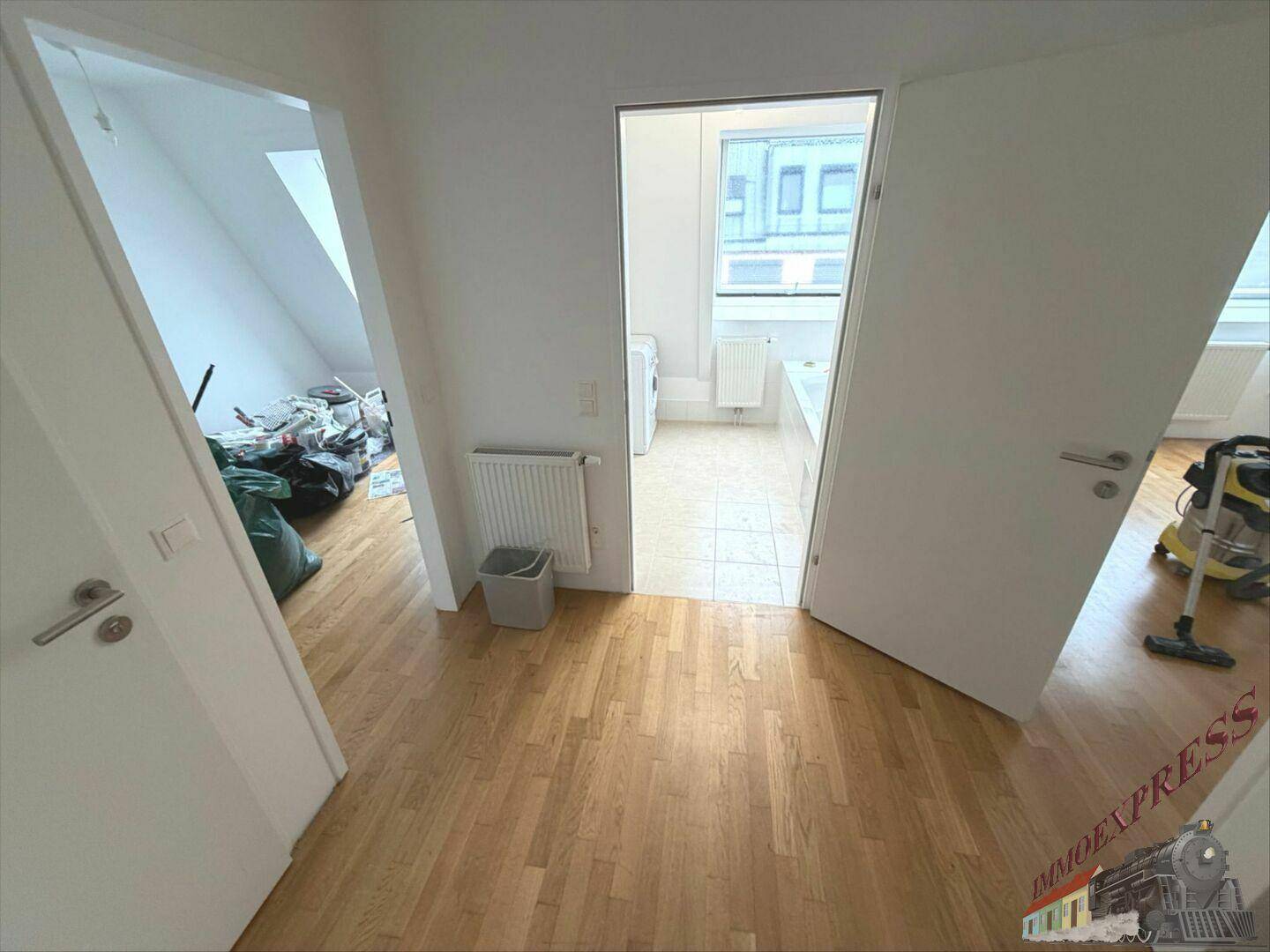 Heller Flur mit Holzboden und Zugang zu verschiedenen Räumen, darunter ein Badezimmer und ein Lagerraum.