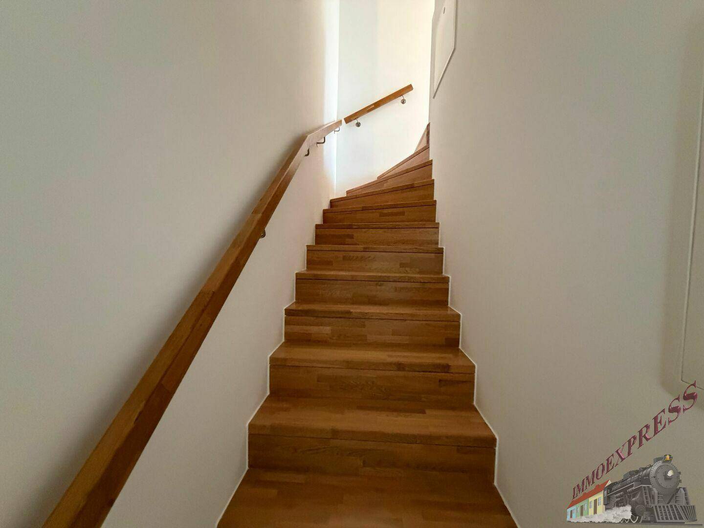 Elegante Holztreppe mit passendem Handlauf, die die verschiedenen Ebenen der Wohnung verbindet.