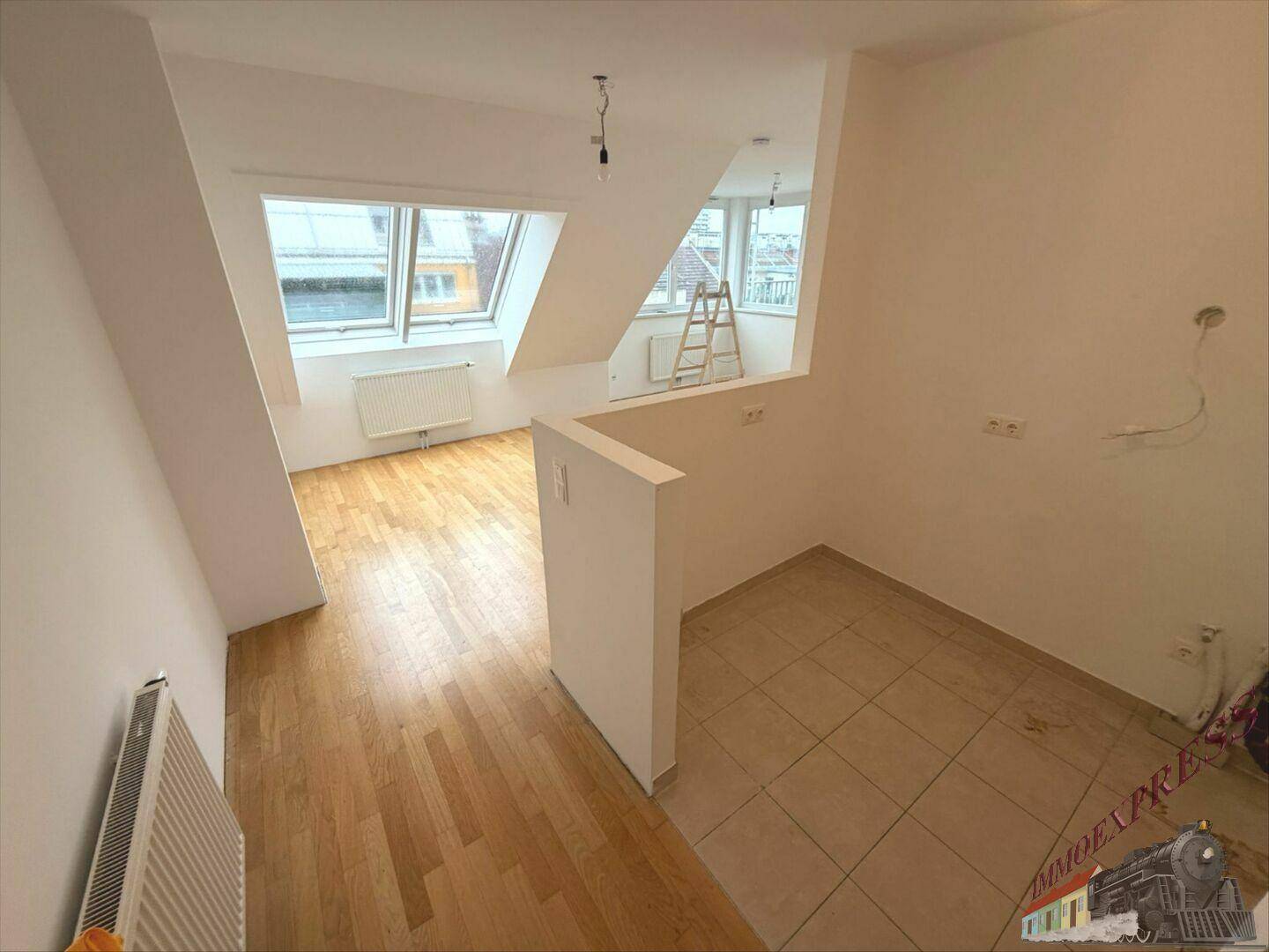 Übergangsbereich im Dachgeschoss mit Holzboden, Fliesen und Dachfenstern für viel Tageslicht.