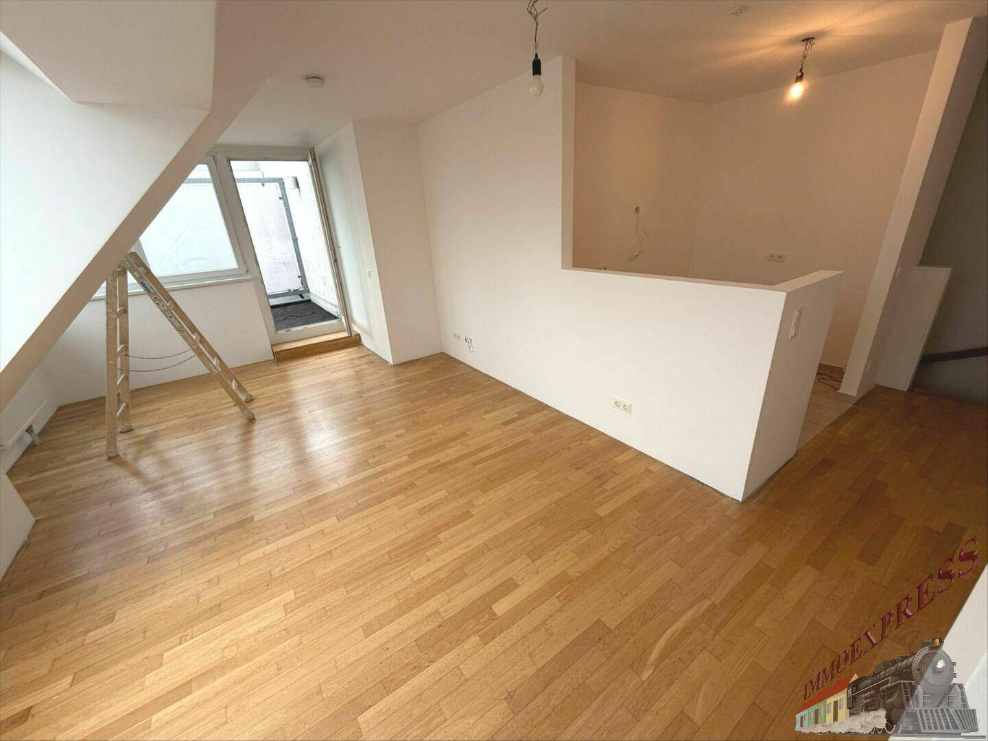 Geräumiger Dachgeschossraum mit hellem Holzboden und offenem Übergang zu einem Außenbereich.