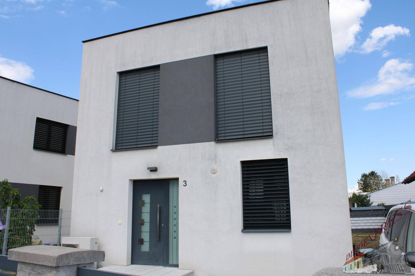 Vorderansicht eines modernen Hauses mit dunkler Eingangstür und geschlossenen Fensterläden.