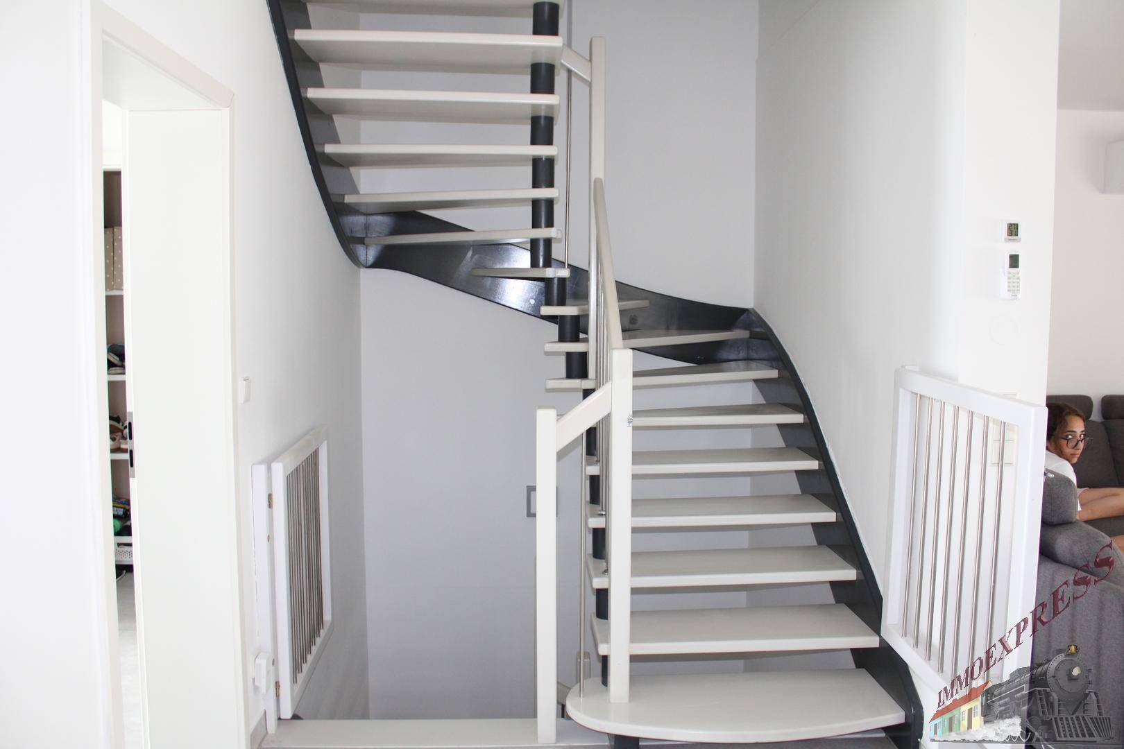 Moderne Treppe mit weißen Stufen und dunklen Akzenten, die in die obere Etage führt.
