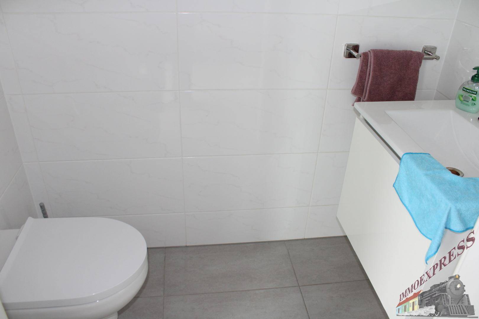 Badezimmer mit Toilette und Badewanne, ausgestattet mit weißen Wandfliesen.