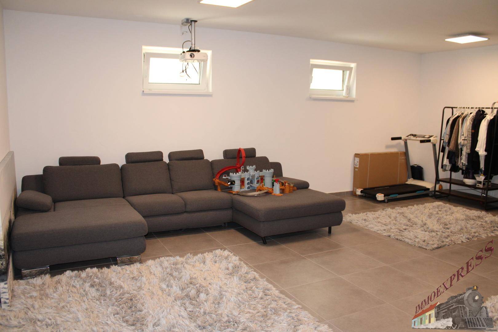 Ausgebauter Kellerraum als Wohn- und Freizeitbereich mit Sofa, Beamer und Fitnessgeräten.