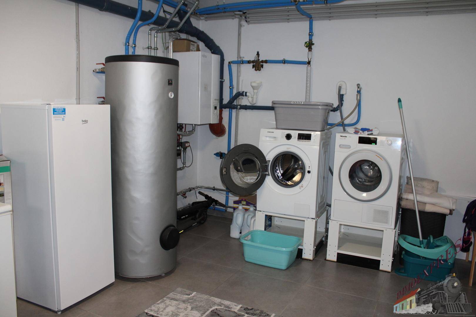 Hauswirtschaftsraum mit Warmwasserspeicher, Waschmaschine und Trockner für praktische Nutzung.