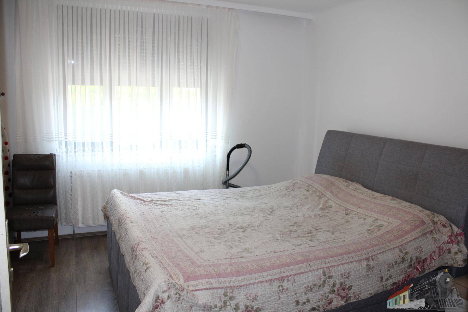 Schlafzimmer mit Doppelbett, hellem Fenster und schlichtem Design.