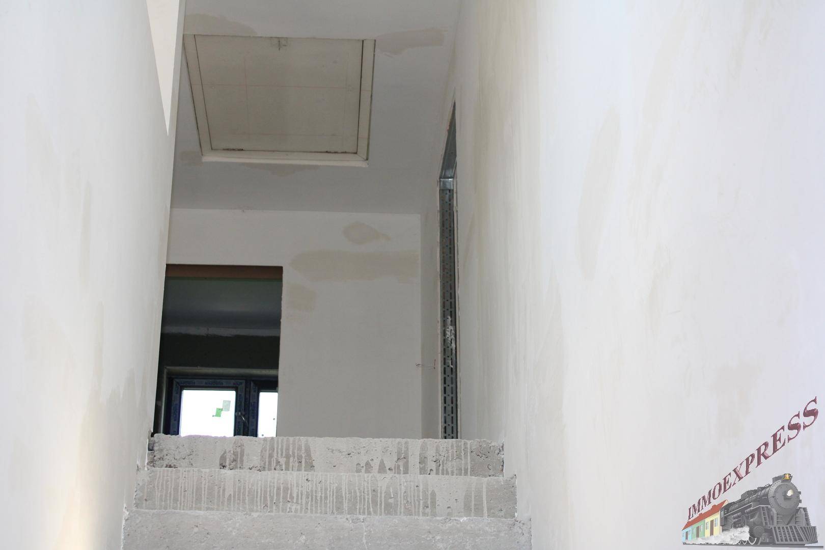 Unfertiges Treppenhaus mit Betonstufen und Zugang zum Dachboden.