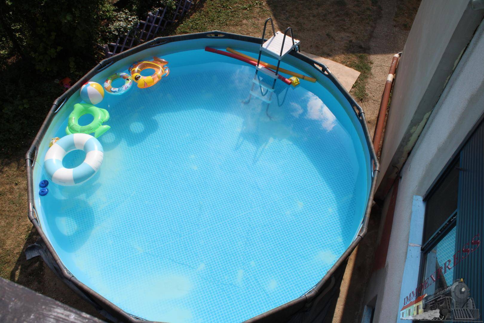 Aufstellpool im Garten mit aufblasbaren Spielzeugen und Leiter.