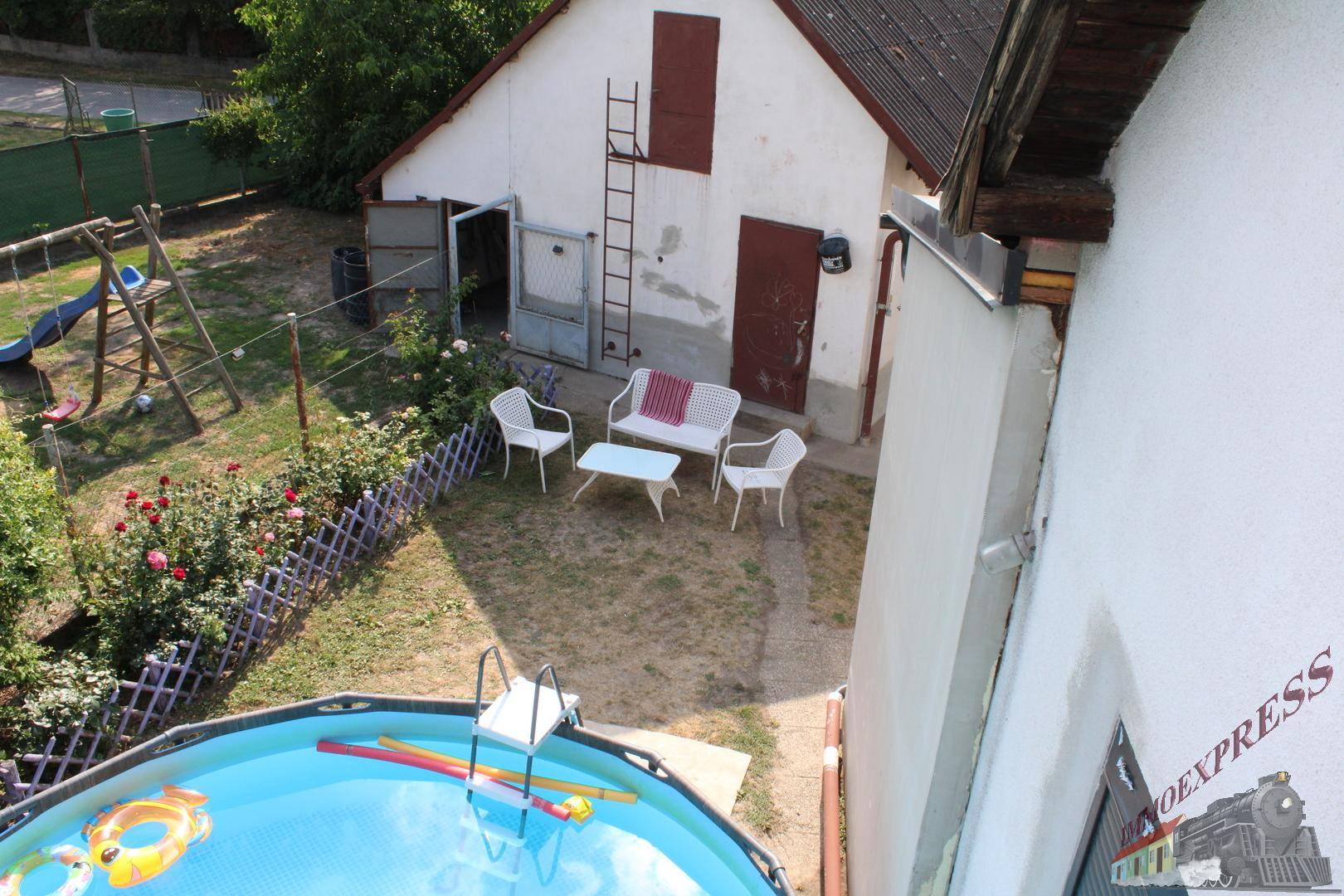 Gartenbereich mit Aufstellpool, Sitzgelegenheiten und Blick auf das Nebengebäude.