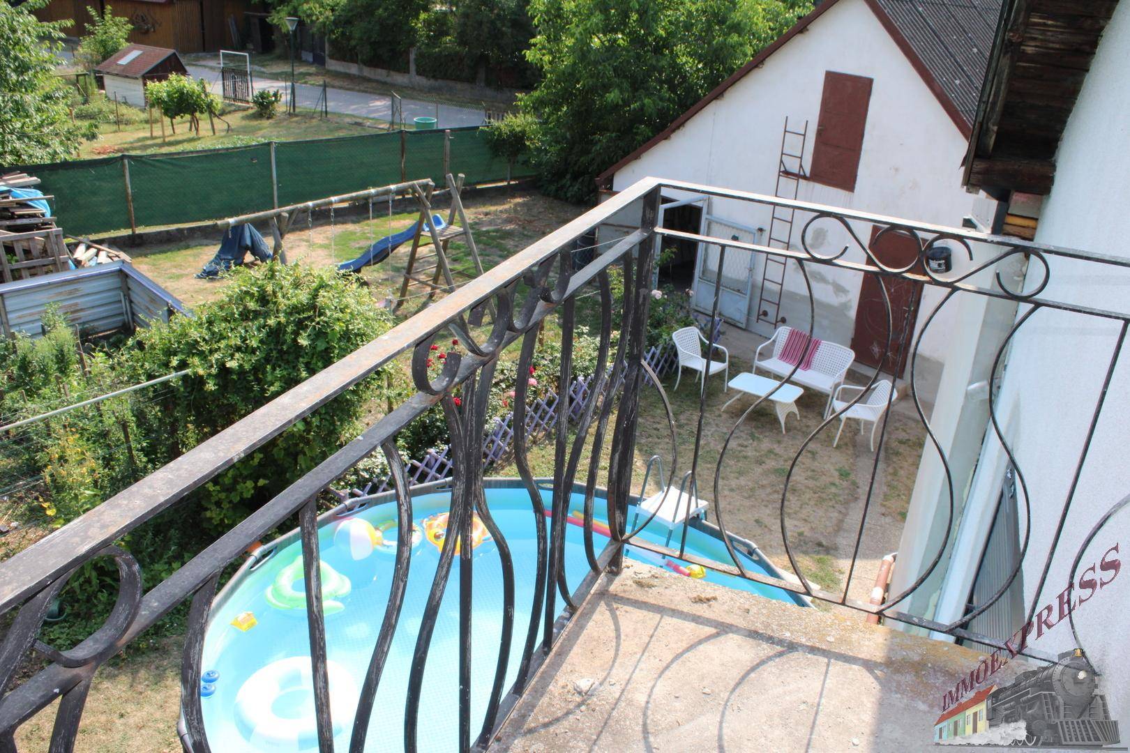 Balkon mit schmiedeeisernem Geländer und Blick auf den Garten mit Pool.