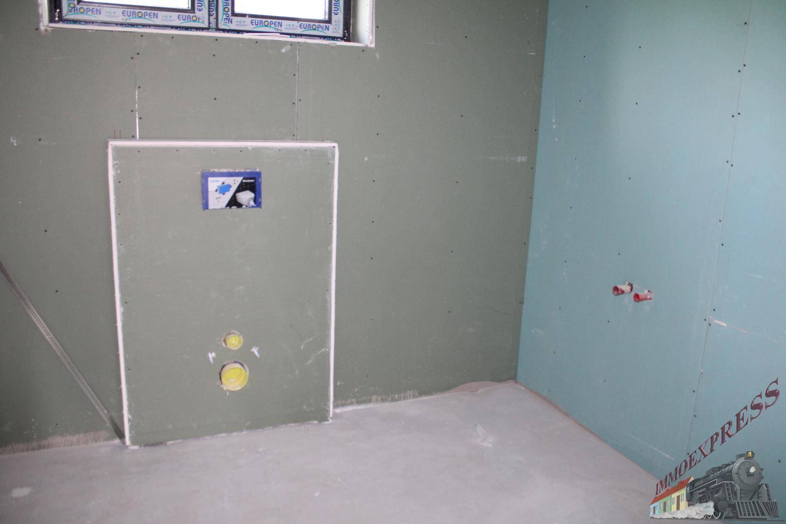 Unfertiges Badezimmer mit Trockenbauwänden und vorbereiteten Installationen.