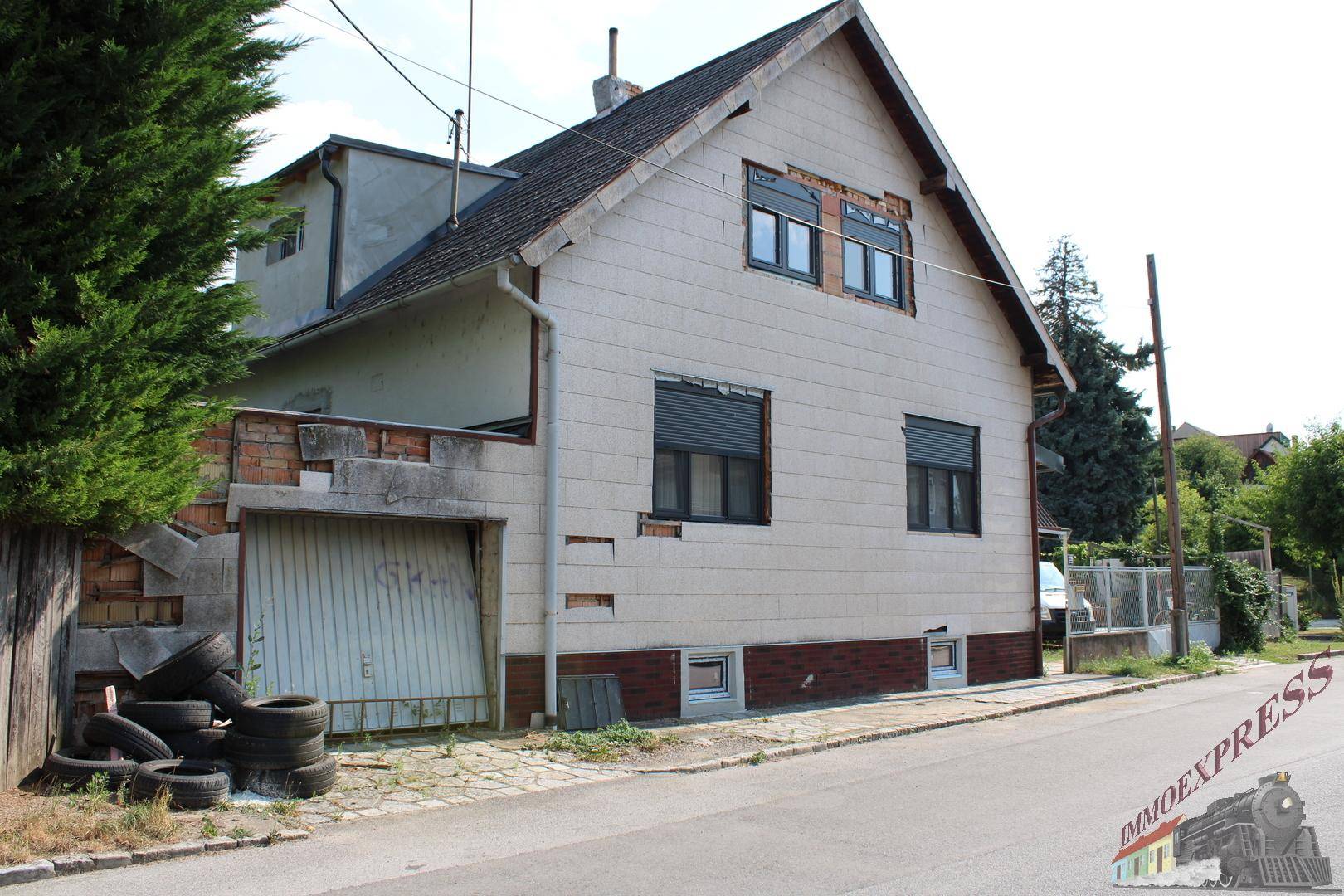 Seitenansicht eines Hauses mit Garage und Rollläden an den Fenstern.