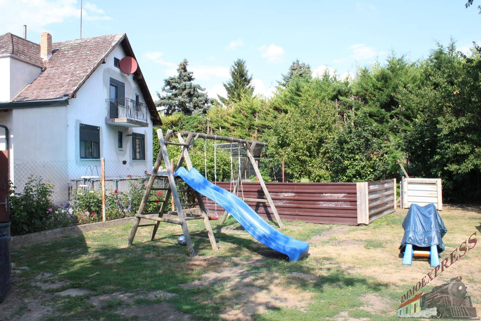 Großer Garten mit Kinderspielplatz, Rutsche und Schaukeln hinter dem Haus.