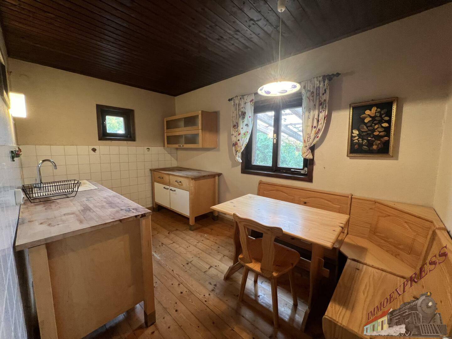 Rustikale Küche mit Holzdielenboden, Holzmöbeln und einem kleinen Fenster.