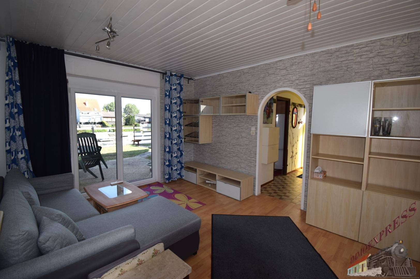 Helles Wohnzimmer mit Zugang zur Terrasse, Holzboden und bequemer Eckcouch, modern eingerichtet.