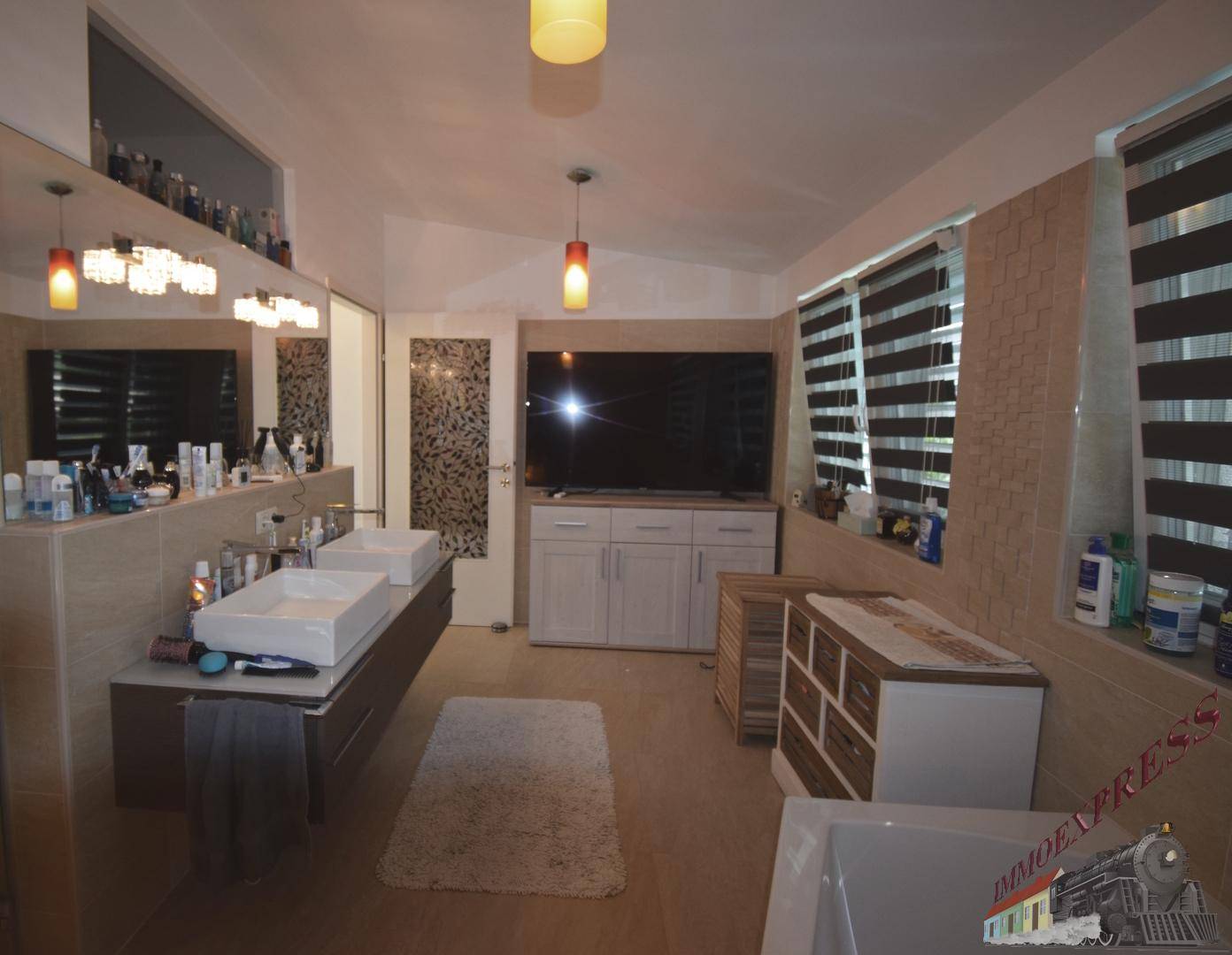 Geräumiges Badezimmer mit Doppelwaschbecken, Badewanne und großen Fenstern.