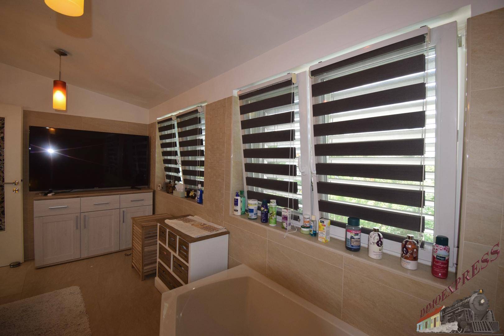 Helles Badezimmer mit Badewanne, Fenster und modernen Jalousien.