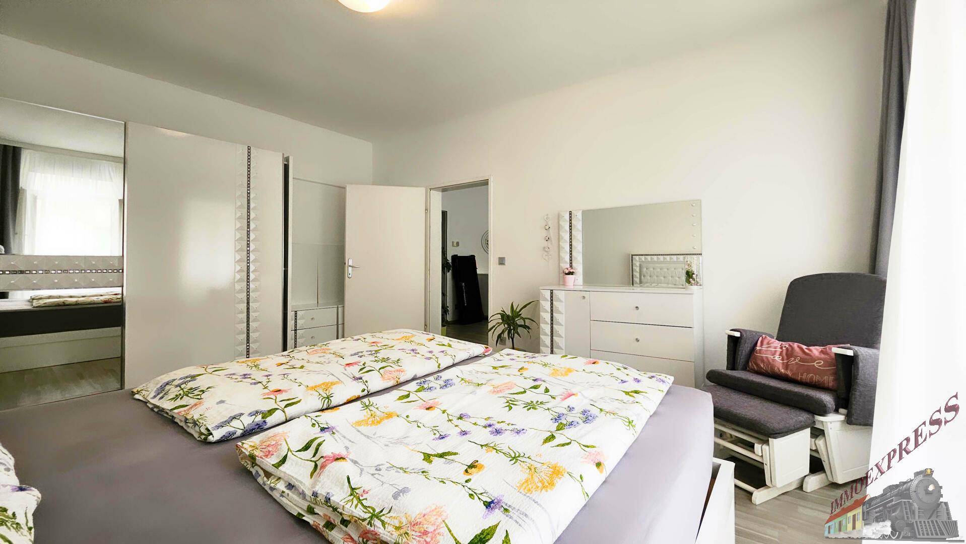 Schlafzimmer mit Doppelbett, Kleiderschrank und Kommode, hell und funktional eingerichtet.