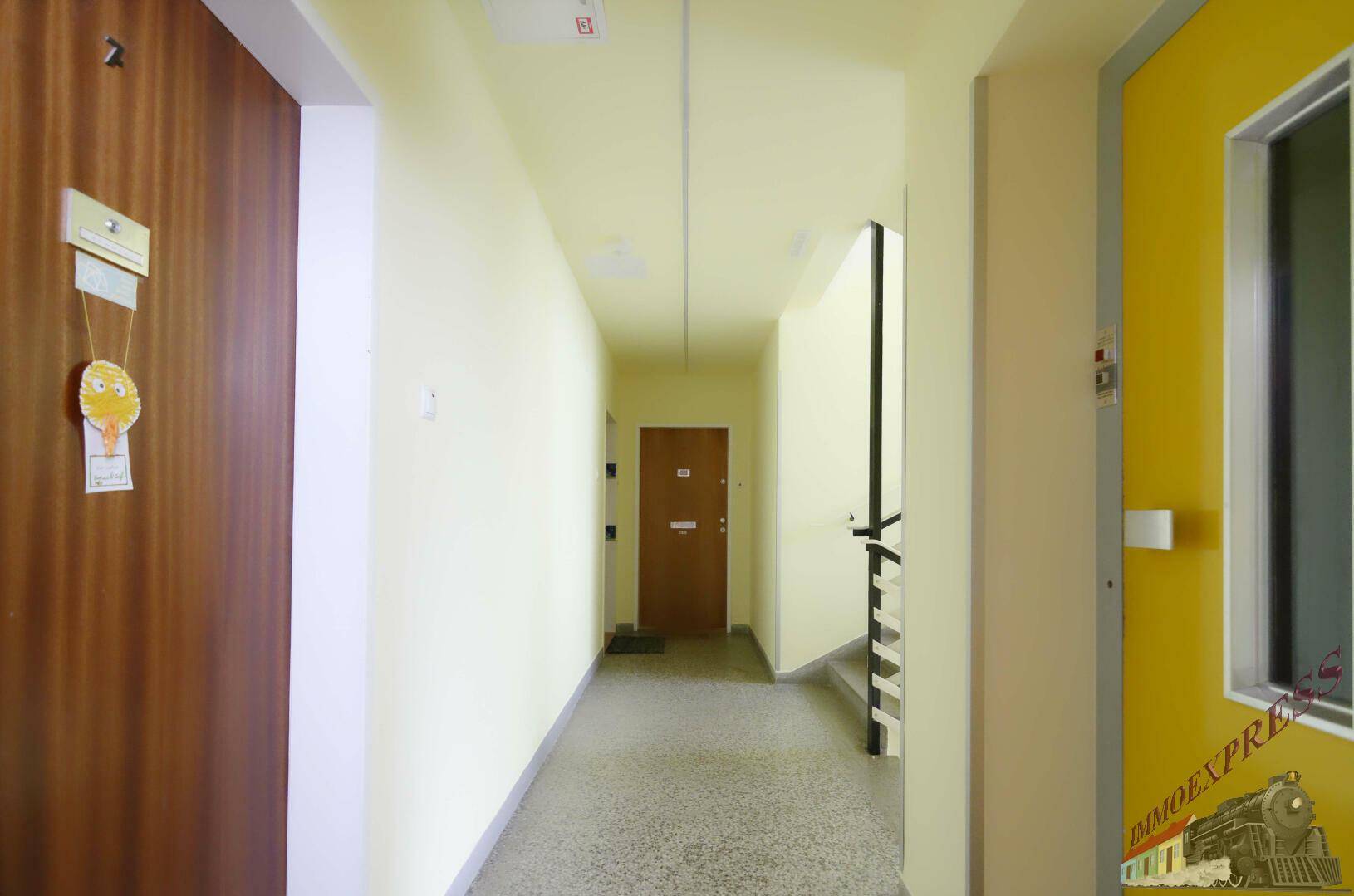 Heller Hausflur mit mehreren Wohnungstüren und Treppenaufgang in einem Mehrfamilienhaus.