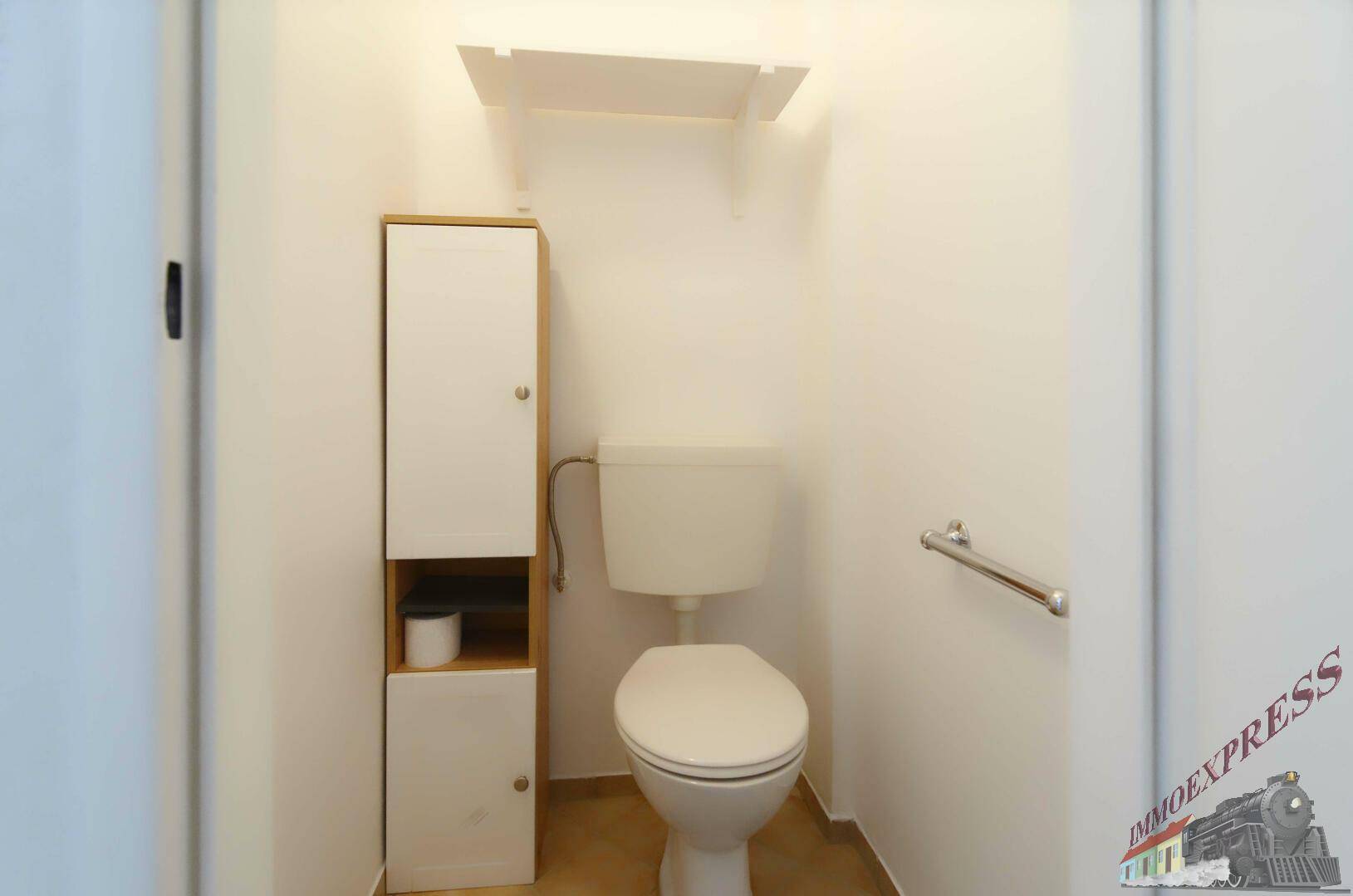 Kleines separates WC mit Toilette, schmalem Schrank und Fliesenboden.