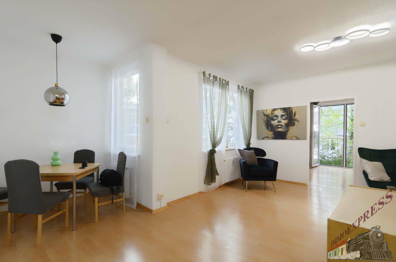 Geräumiger Wohn-Essbereich mit Holzfußboden, Essgruppe und Zugang zum Balkon.