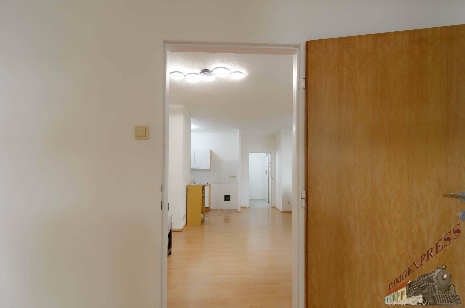 Blick durch eine Tür in den hellen Wohnbereich mit durchgehendem Holzfußboden und offener Gestaltung.