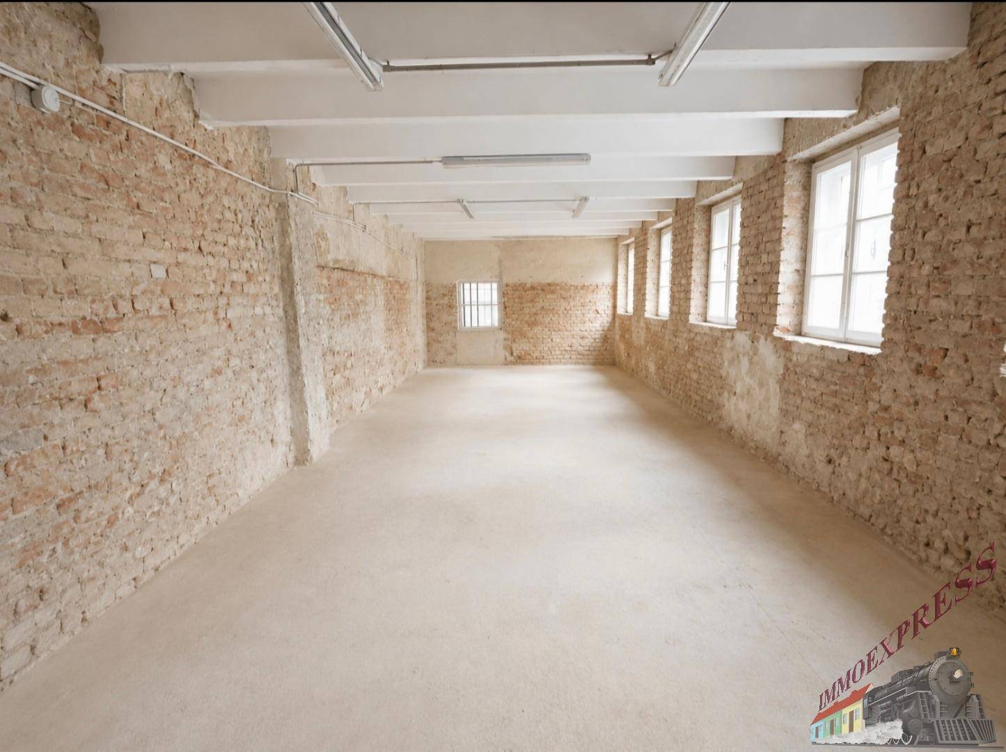 Geräumiger Innenraum mit freiliegenden Ziegelwänden, Betonboden und hohen Decken, bereit zur Neugestaltung.