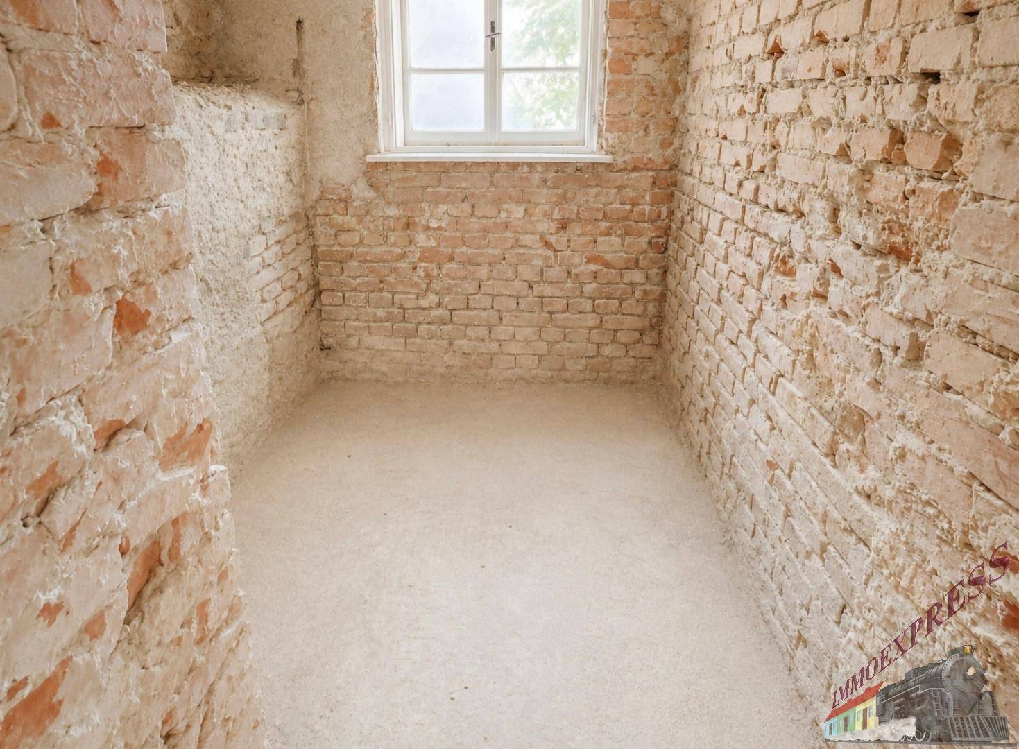 Kleinerer Raum mit unverputzten Ziegelwänden und einem Fenster, ideal für Lagerung oder als Abstellraum.
