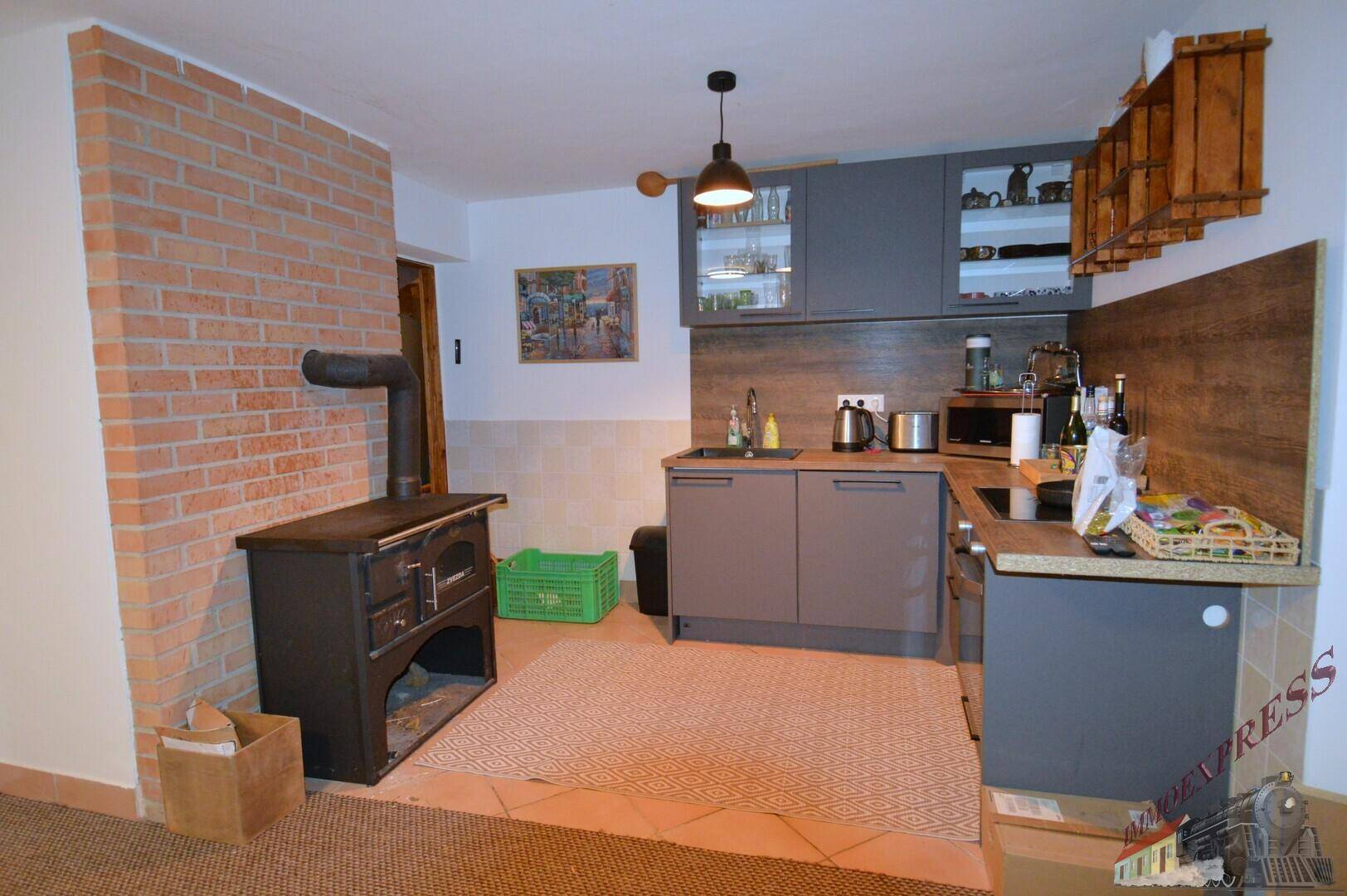 Kleine Küche mit Holzofen und Backsteinwand, ideal für rustikales Kochen.