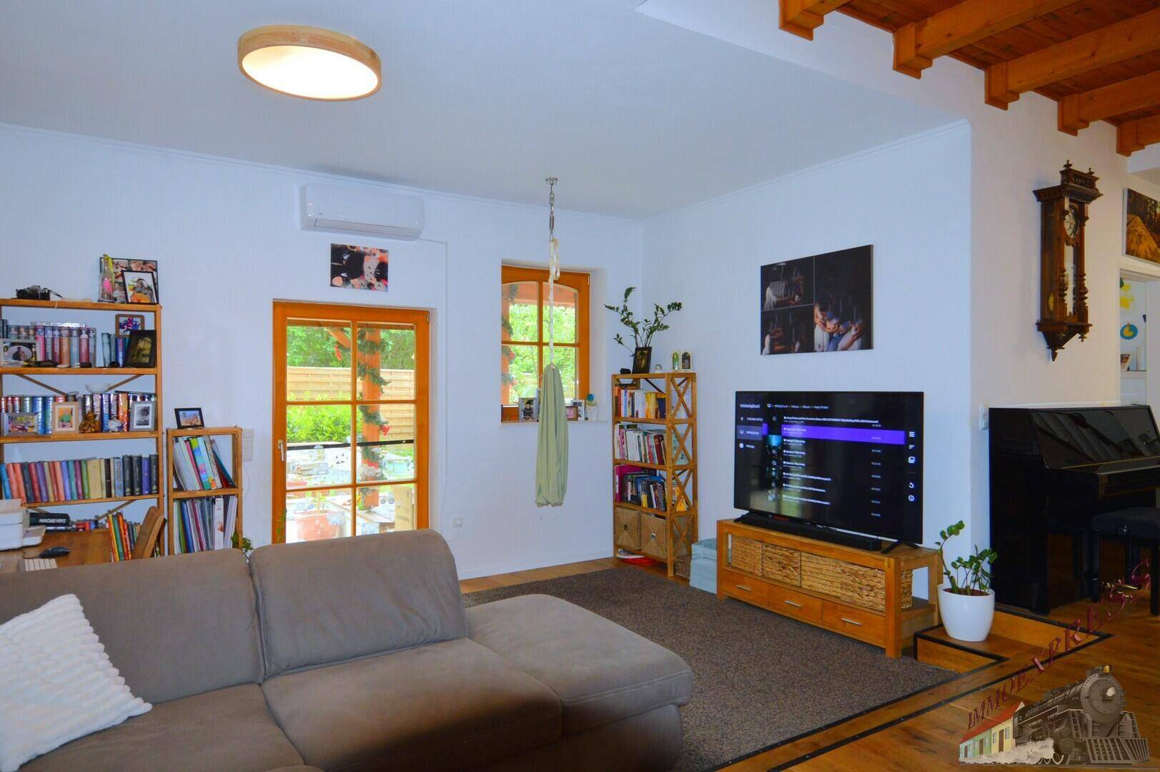 Gemütliches Wohnzimmer mit großem Sofa, Fernseher und Zugang zur Terrasse, ideal zum Entspannen.