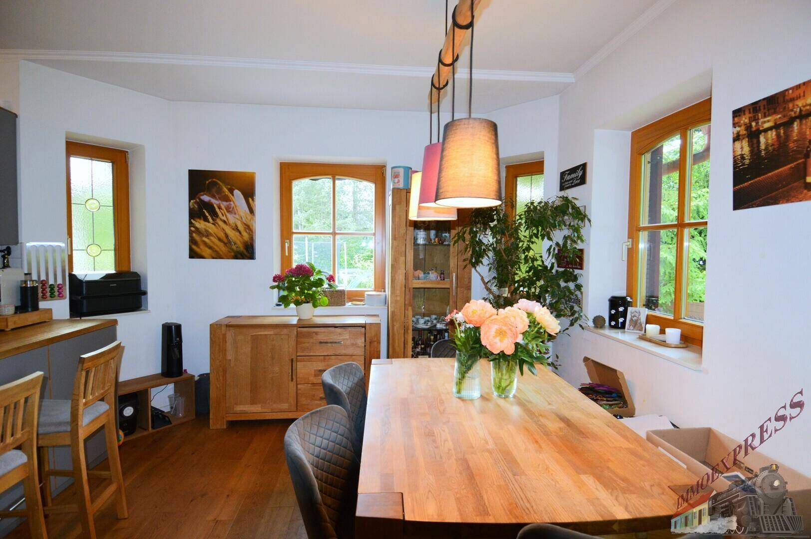 Geräumiger Essbereich mit Holztisch, bequemen Stühlen und viel Tageslicht durch große Fenster.