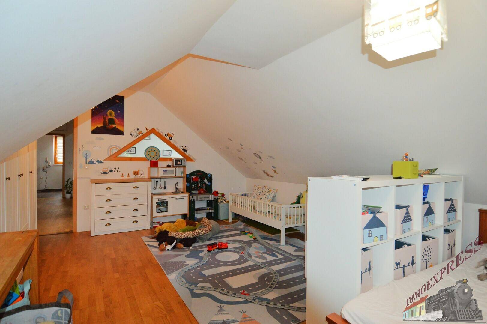 Helles Kinderzimmer im Dachgeschoss mit Spielzeug, Bett und Holzboden.
