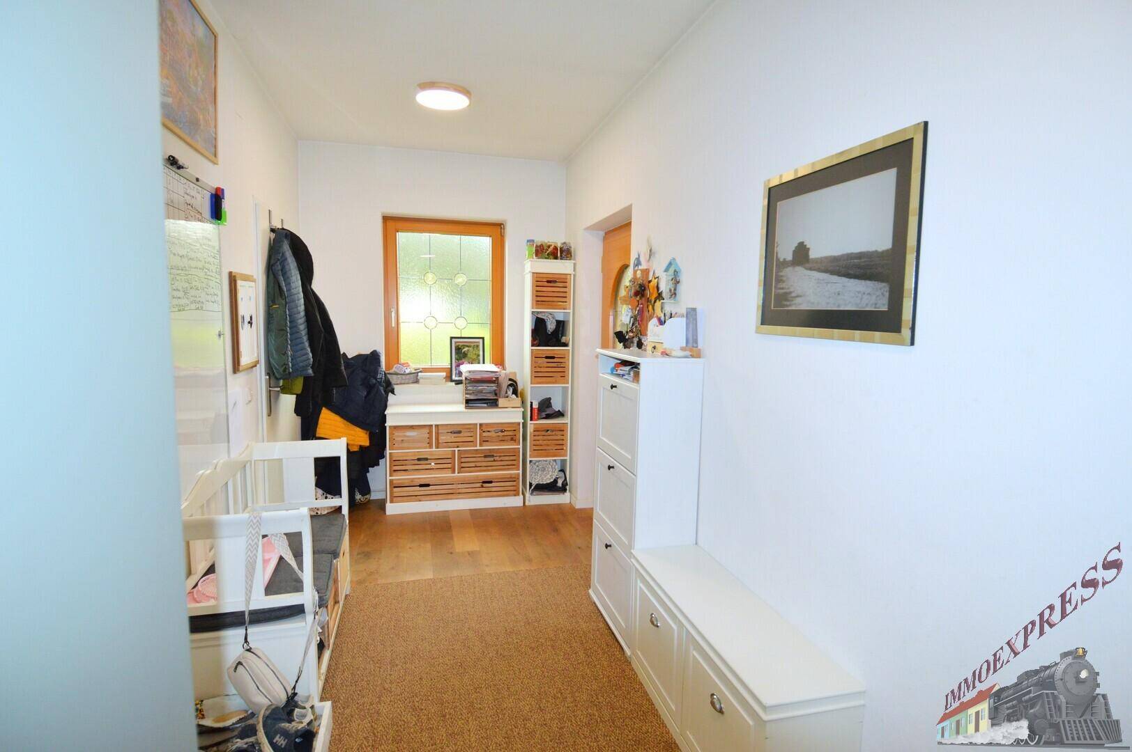 Heller Eingangsbereich mit Garderobe, Schuhschränken und Holzboden, einladend und funktional.