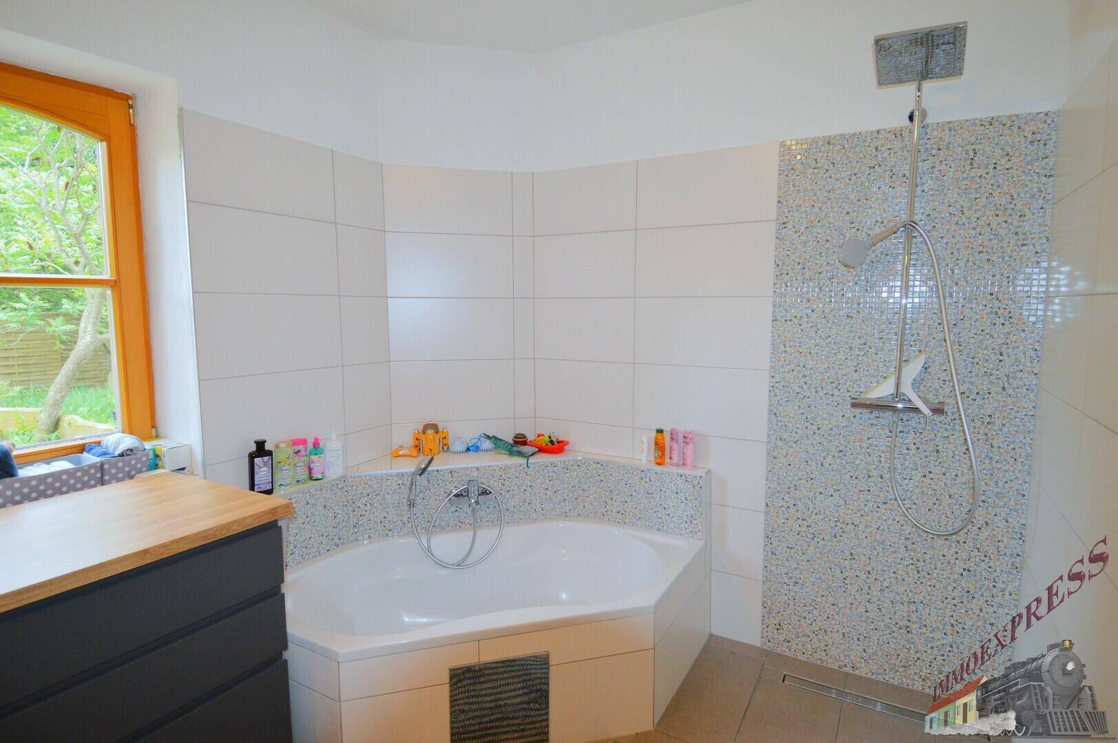 Helles Badezimmer mit Eckbadewanne, Duschbereich und Fenster, modern gefliest und funktional.
