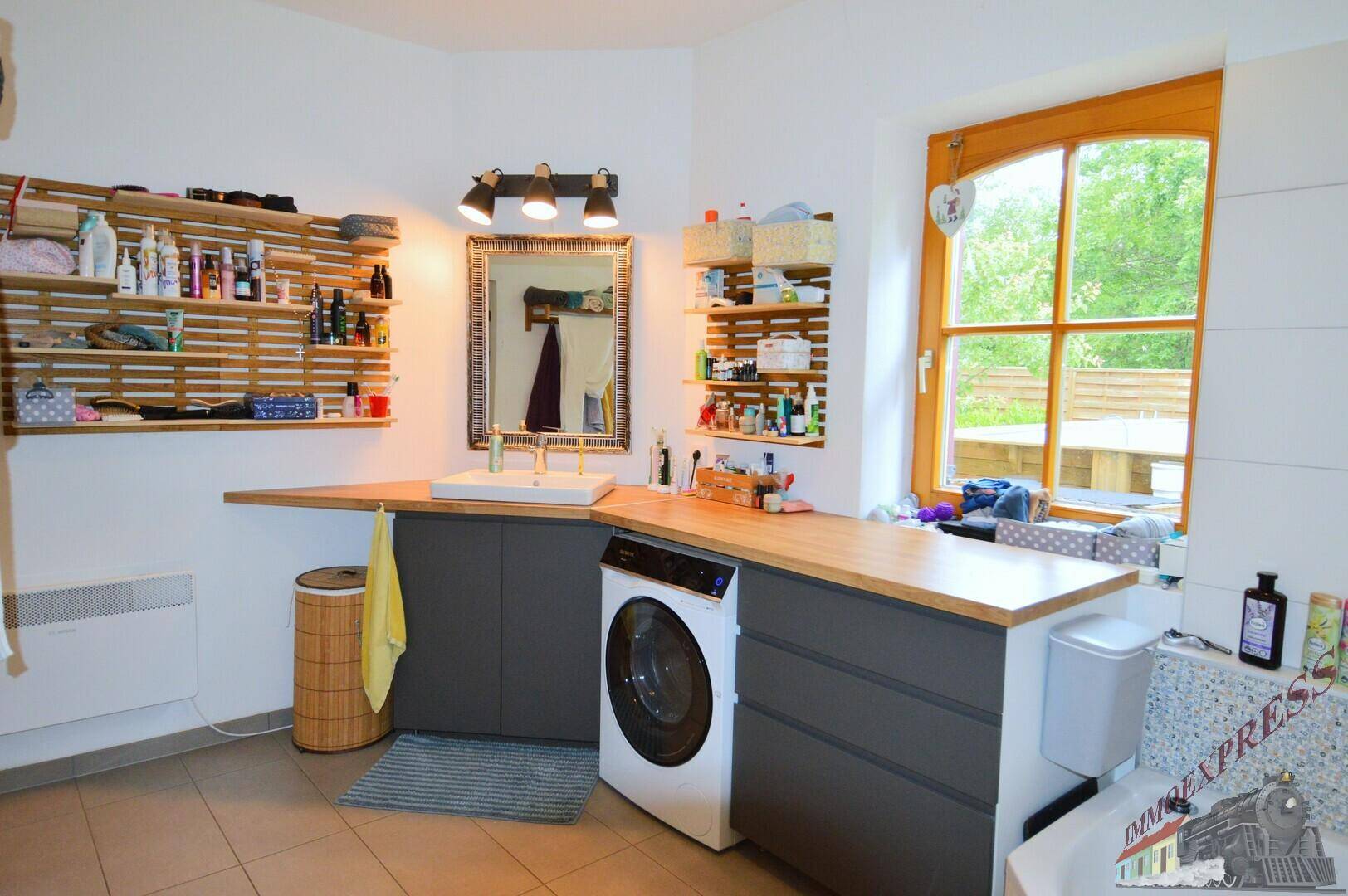 Modernes Badezimmer mit Waschmaschine, großem Waschtisch und Fenster, ausgestattet mit Handtuchheizkörper.