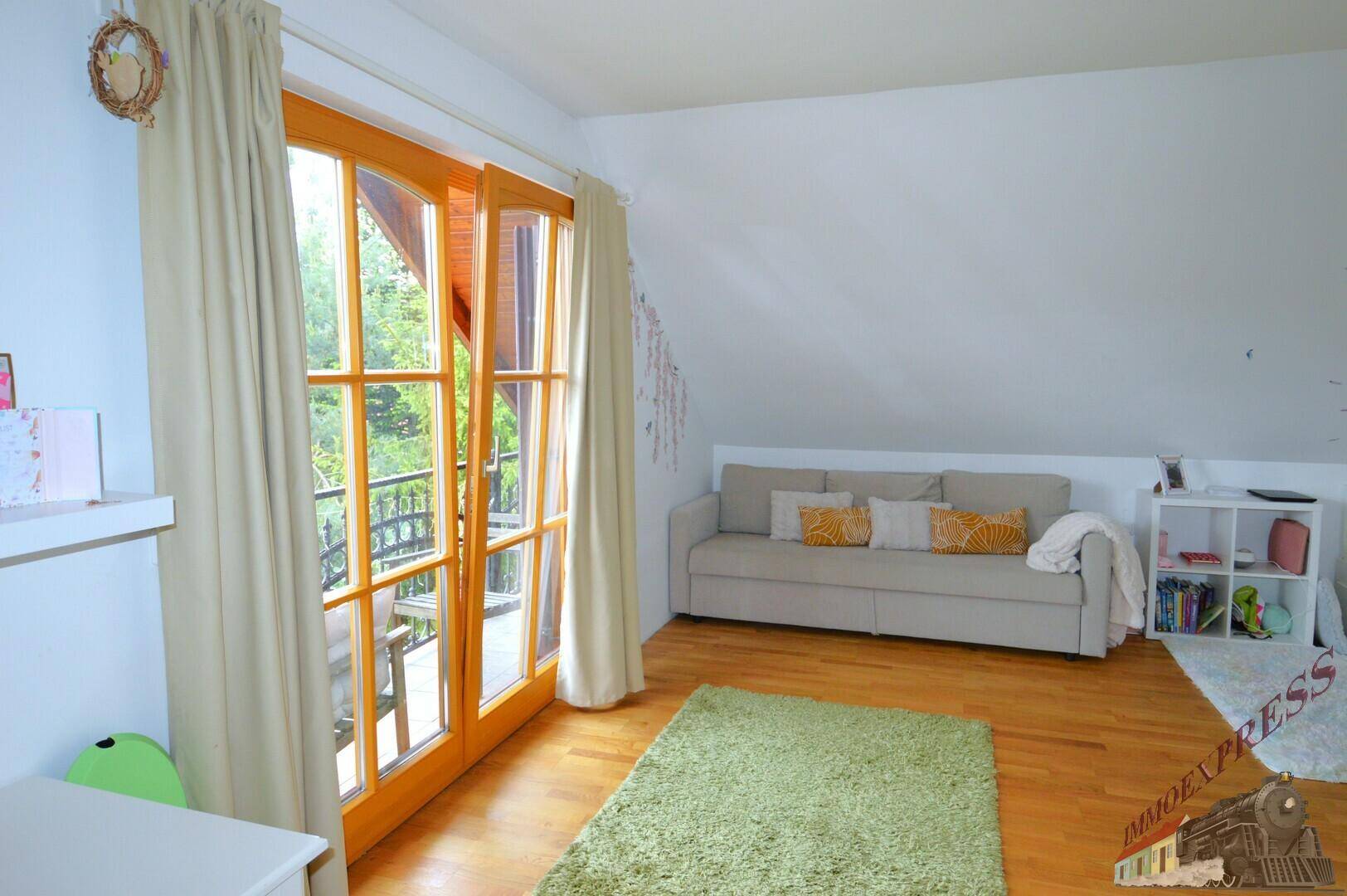Gemütliches Schlafzimmer im Dachgeschoss mit Balkonzugang und Blick ins Grüne.