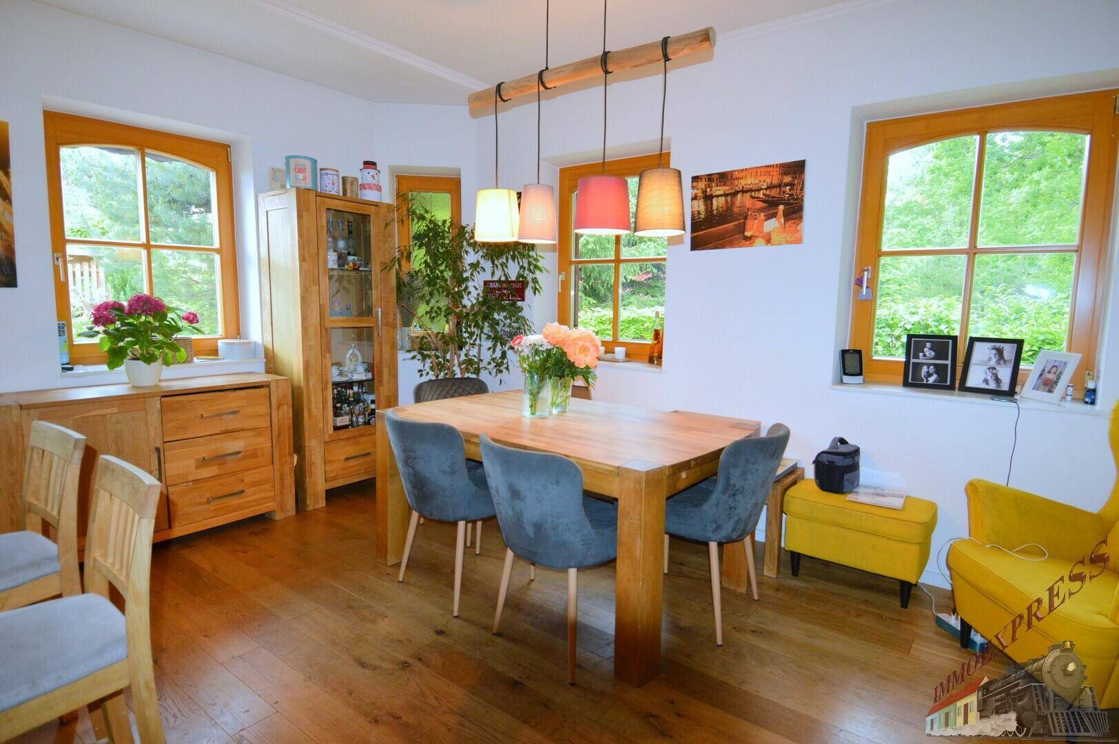Einladender Essbereich mit Holztisch, farbigen Akzenten und Blick in den Garten, ideal für Familien.
