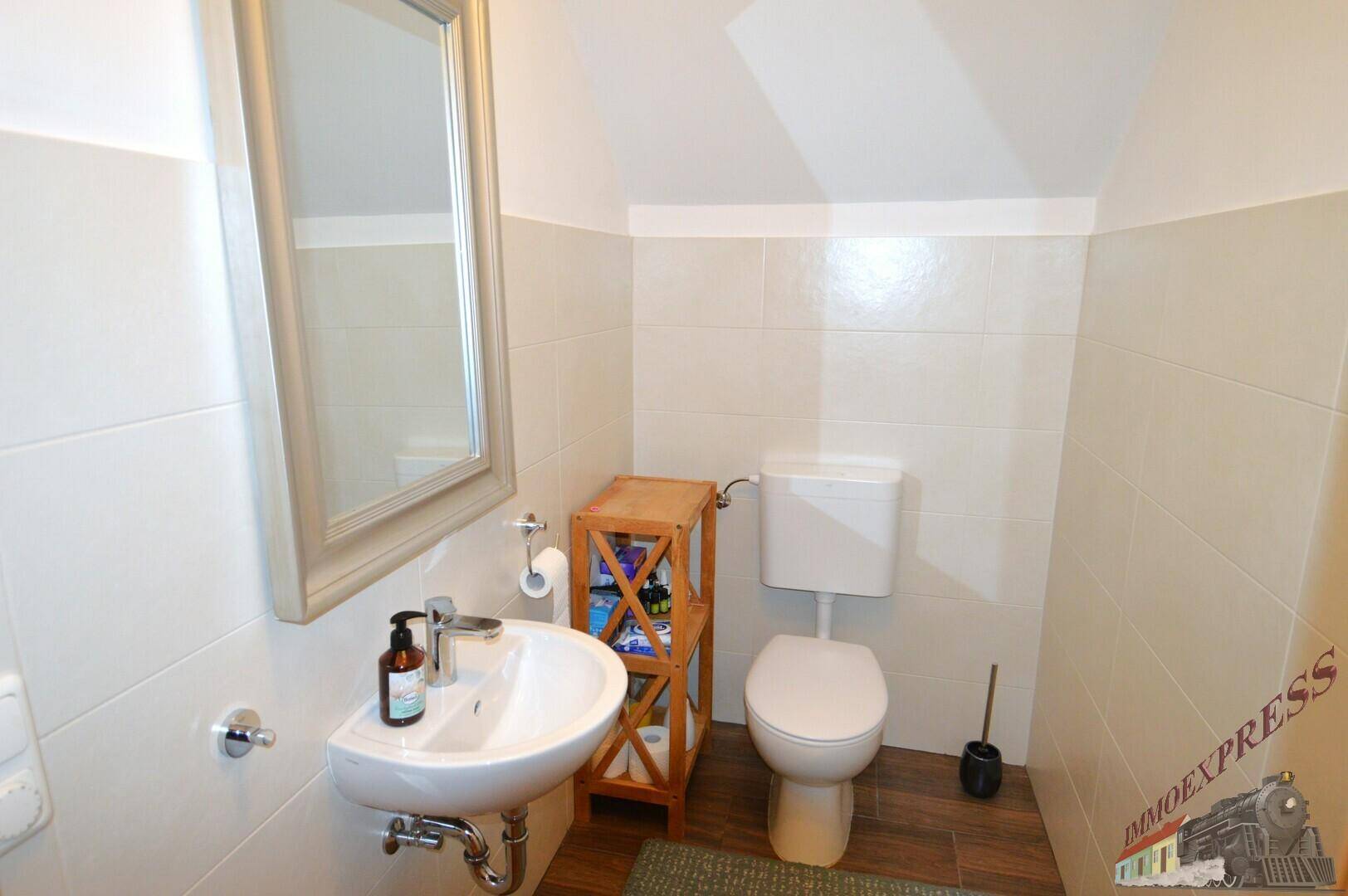 Kleines Gäste-WC mit Waschbecken, Toilette und Spiegel, funktional und sauber.