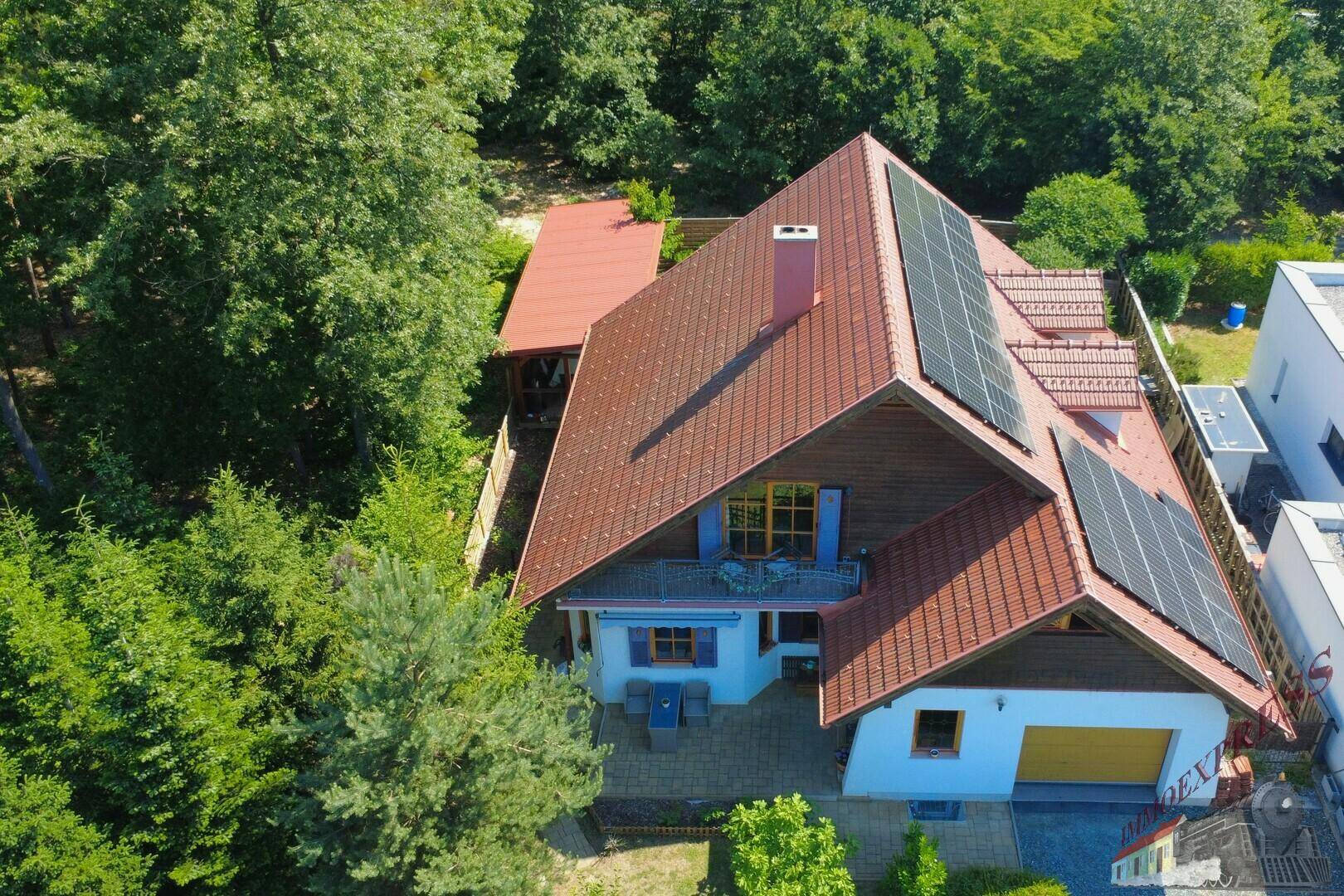 Luftaufnahme des Hauses mit Solaranlage auf dem Dach und umgebendem Grün der Bäume.