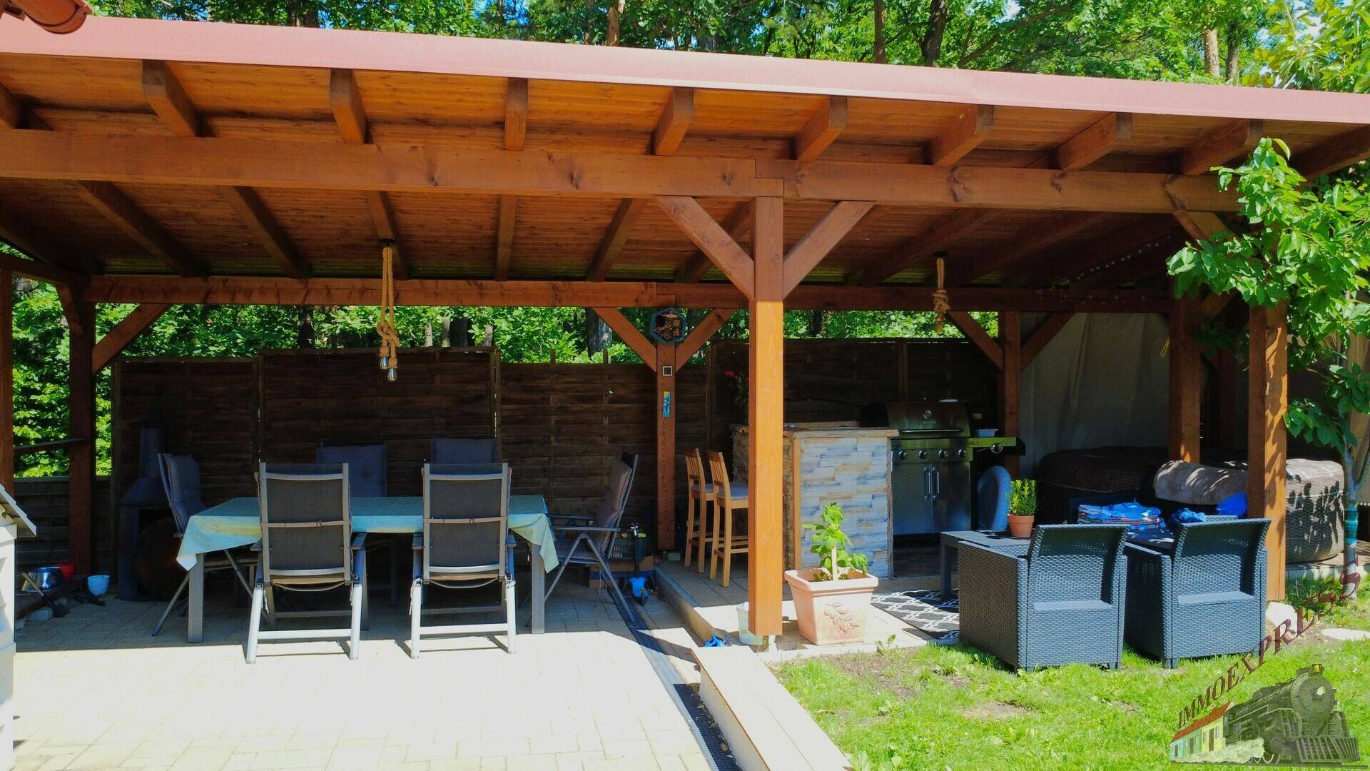 Große überdachte Terrasse mit Essbereich und Grillplatz im Grünen.