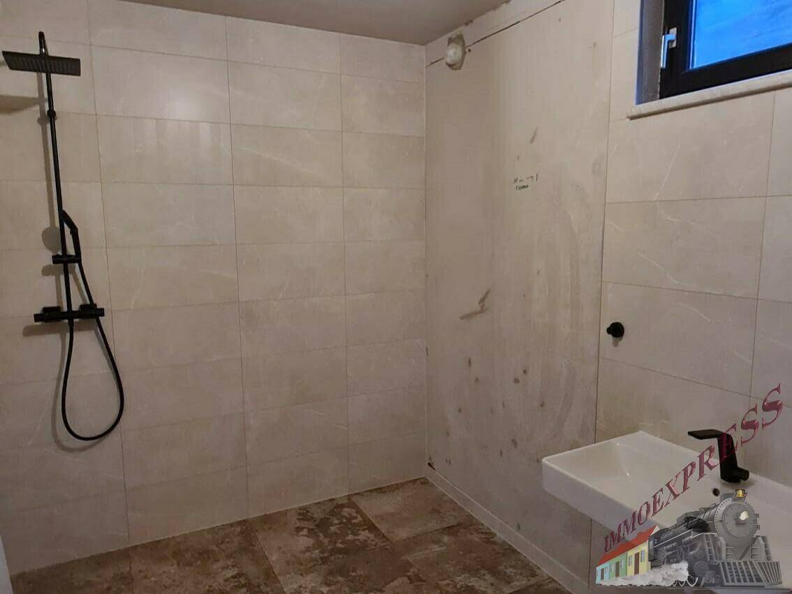 Badezimmer im Rohbau mit Duscharmatur und Waschbecken, bereit für den Ausbau.