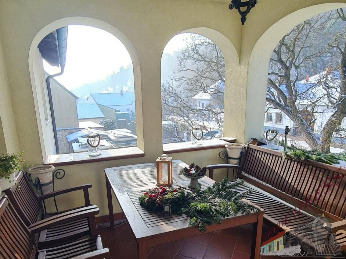 Überdachte Loggia mit Holztisch und Bänken, ideal für Mahlzeiten im Freien.