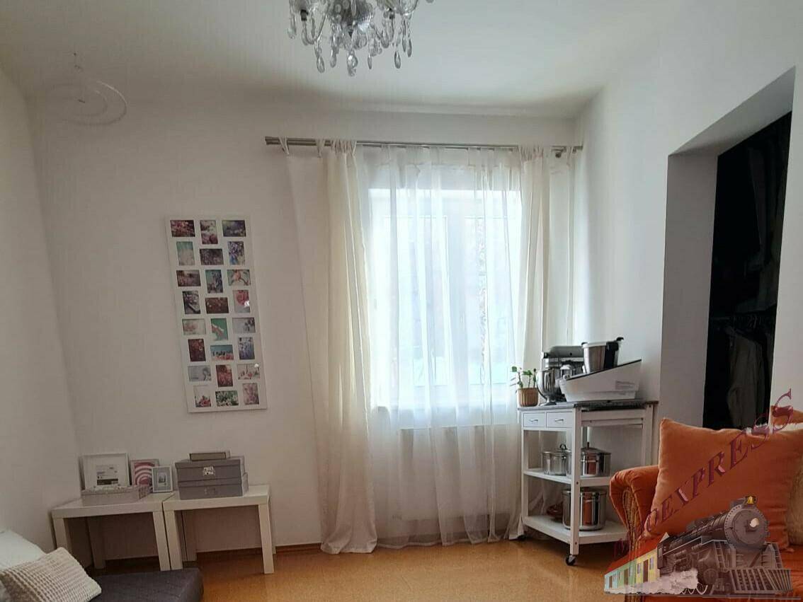 Heller Flur mit Fenster, Gardinen und einem kleinen Beistelltisch.