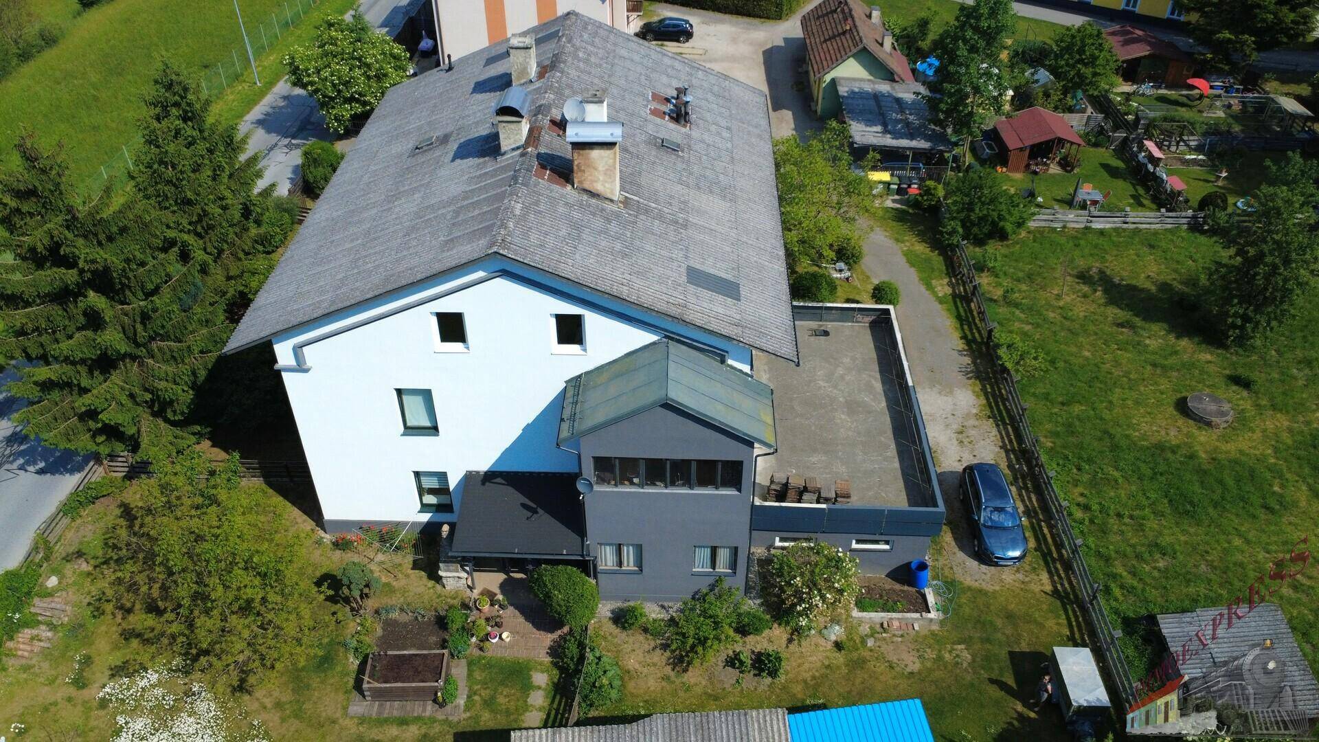 Vogelperspektive des Hauses mit Garten, Flachdach-Erweiterung und umliegender Landschaft.