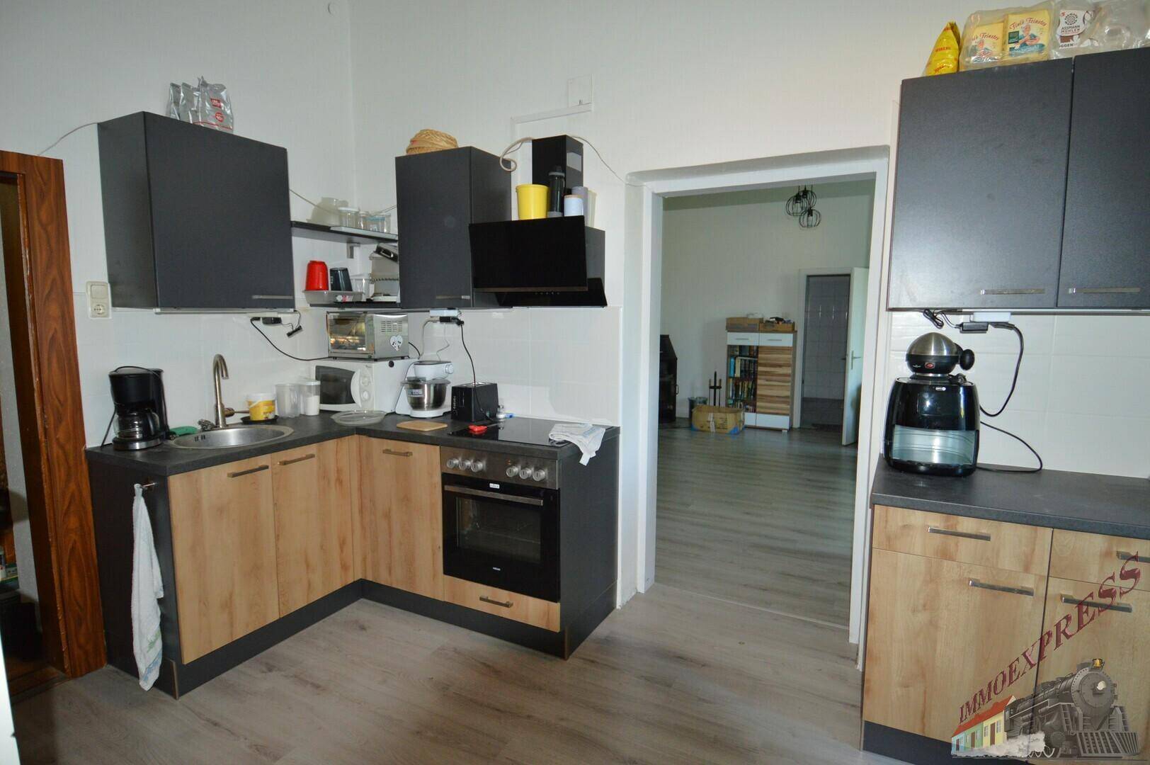 Funktionale Küche mit dunklen und holzfarbenen Schränken, Herd, Backofen und Spüle.