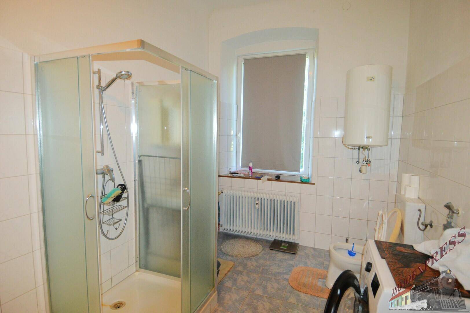 Badezimmer mit Duschkabine, Fenster, Waschmaschine und Warmwasserbereiter.