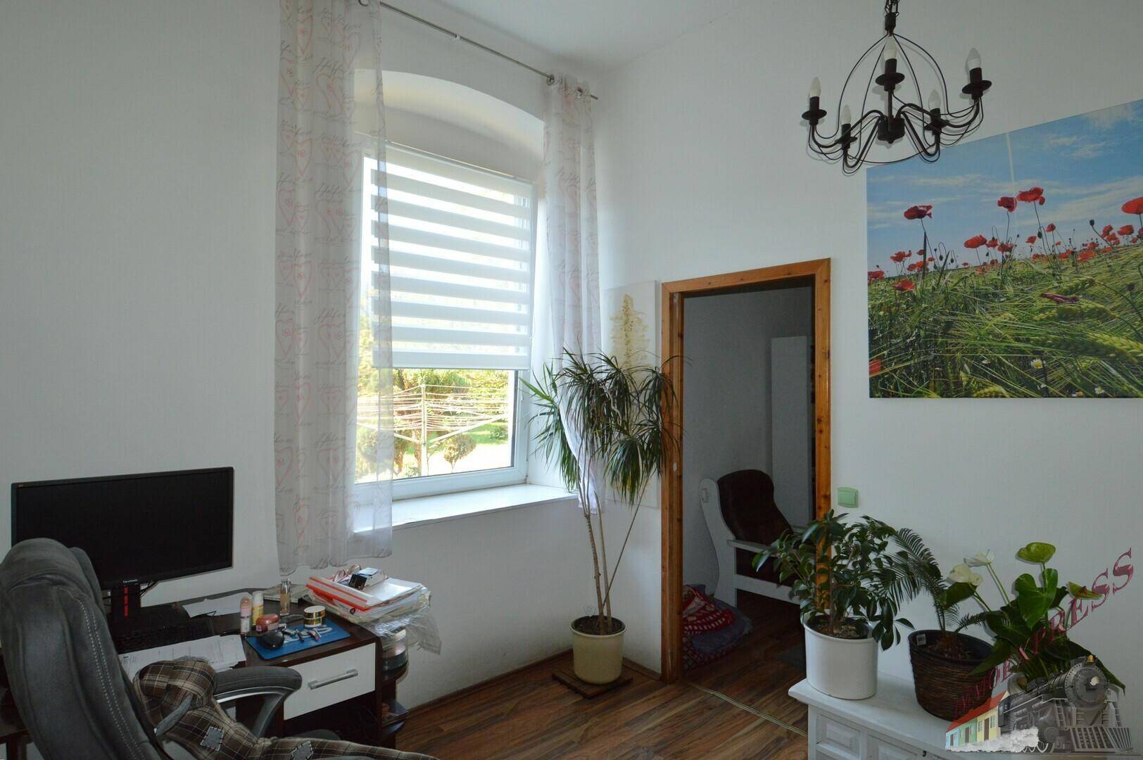 Helles Arbeitszimmer mit Fenster, Schreibtisch und Pflanzen, bietet eine angenehme Arbeitsatmosphäre.