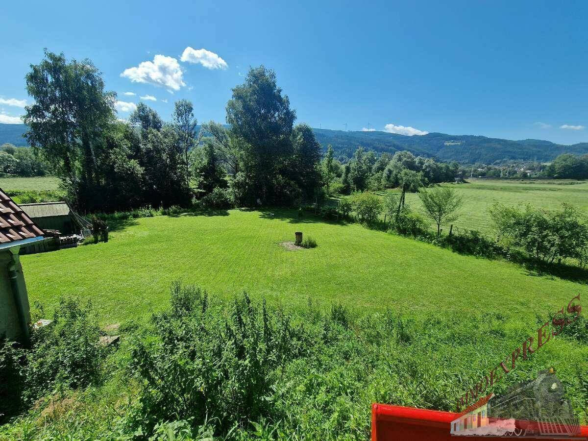 Weitläufige grüne Rasenfläche mit Bäumen und weitem Blick auf die umliegende ländliche Landschaft.