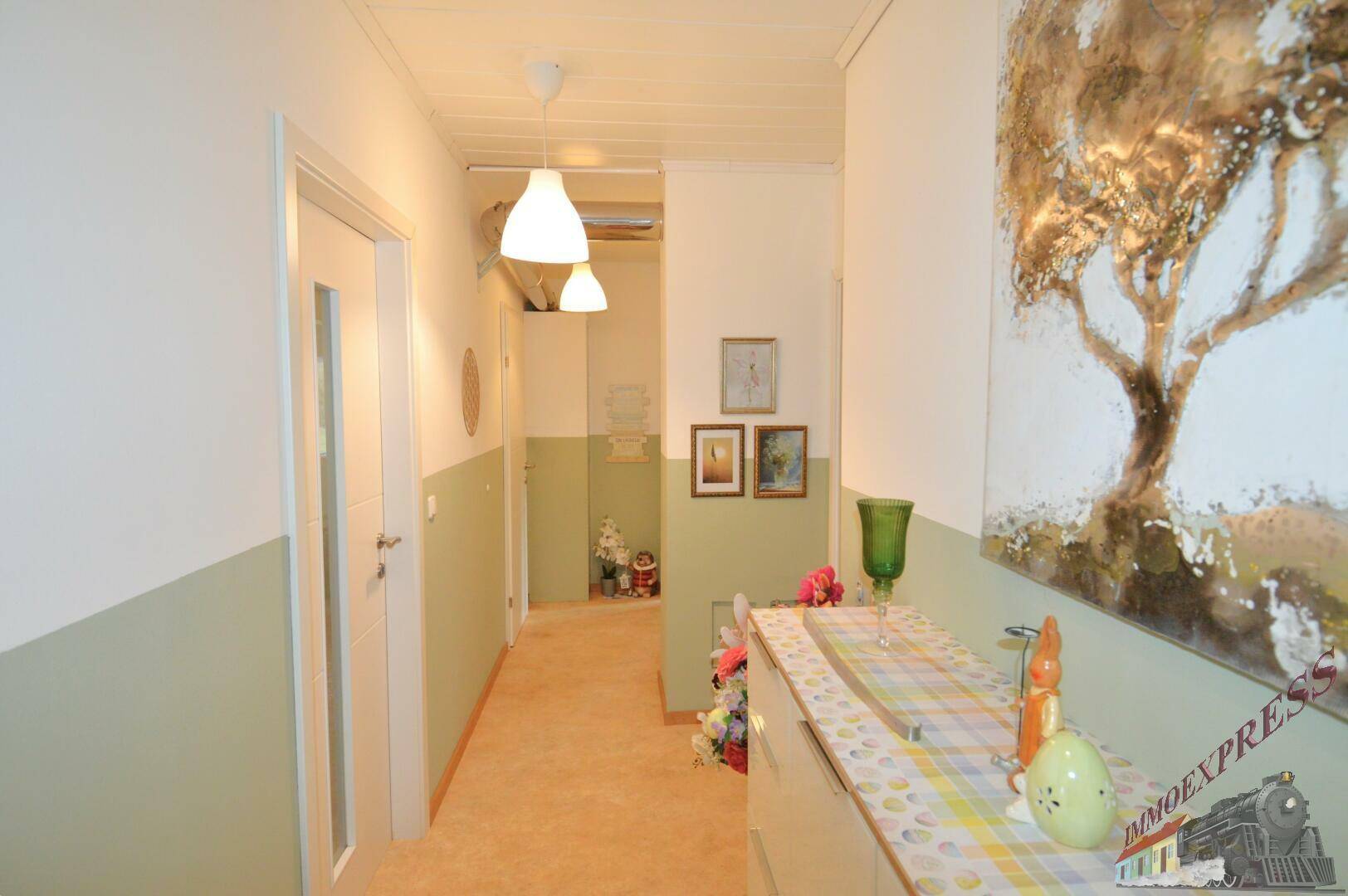Langer Flur mit heller Farbgestaltung, Dekoration und Blick in weitere Räume.